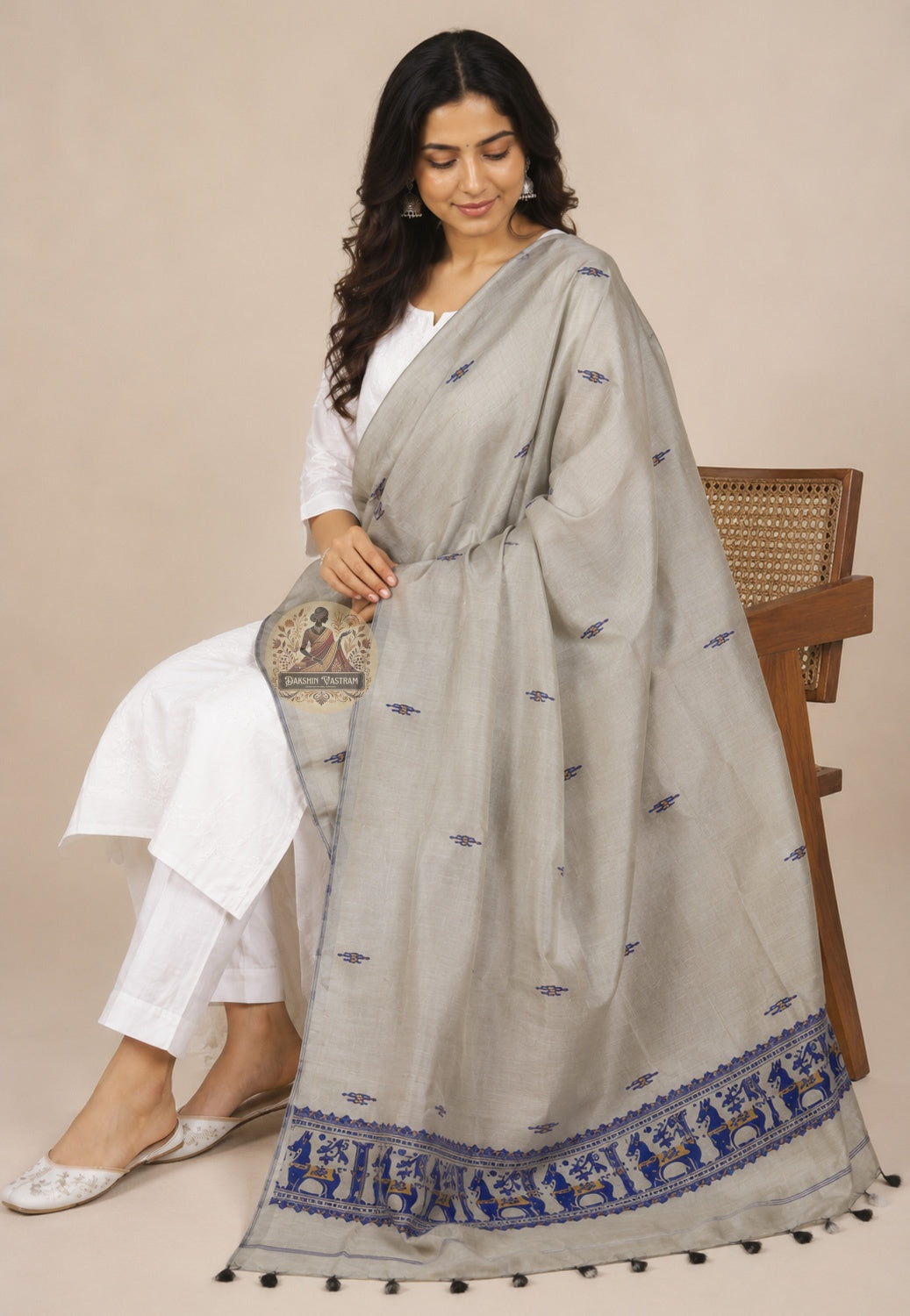 Seated drape view of handwoven Baluchari silk stole in stone grey – royal blue narrative border with woven court figures flowing to floor, perfect for Puja and festive occasions