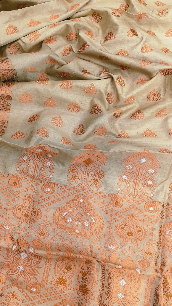 Elegant woman draped in a natural golden Muga silk handloom saree at a formal evening event — Dakshin Vastram UK